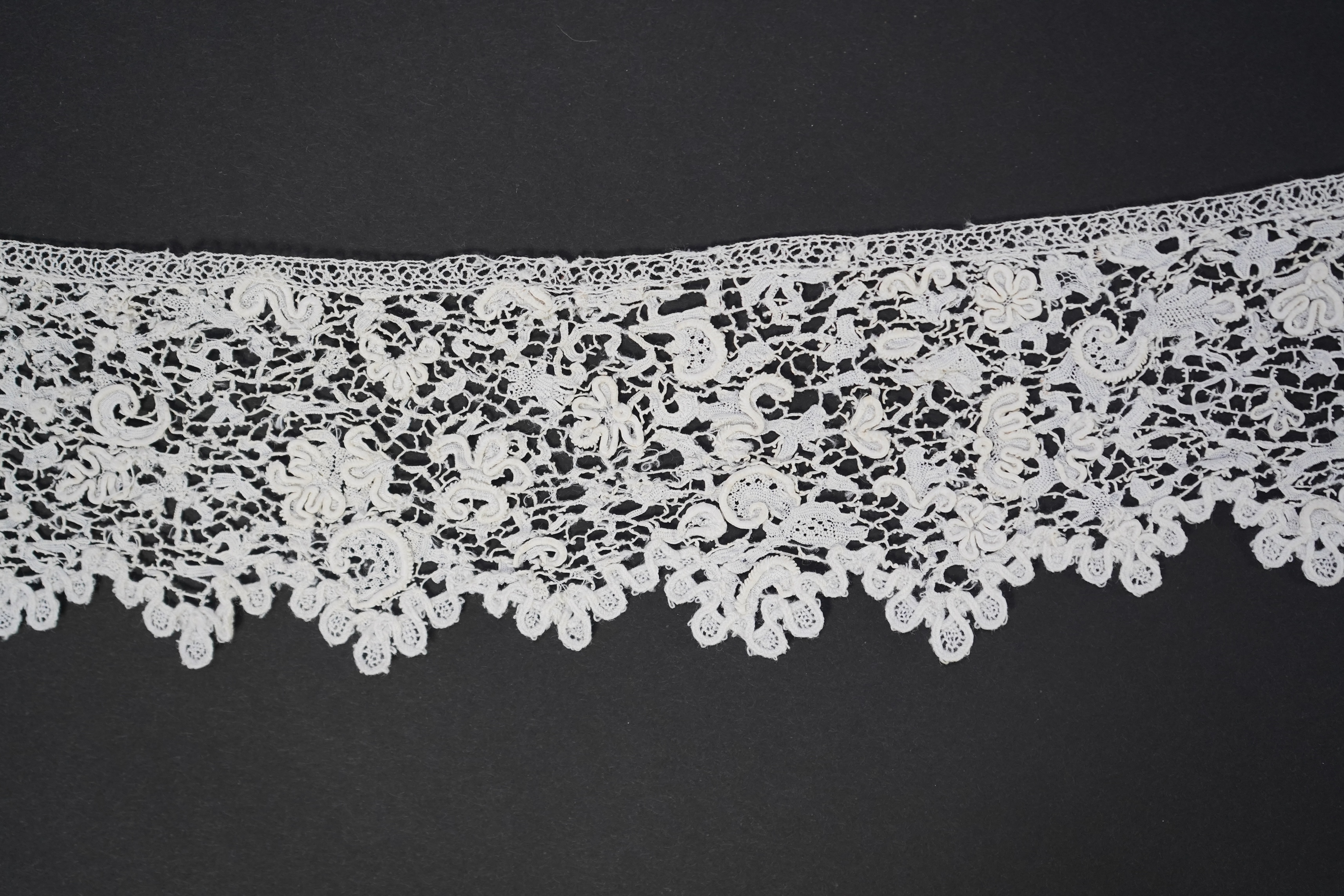 A late 17th century wide flounce of Point de France needle lace, together with a narrower flounce, both with raised elements of the design in the style of Point de Rose, but less so. This lace was very popular with the F